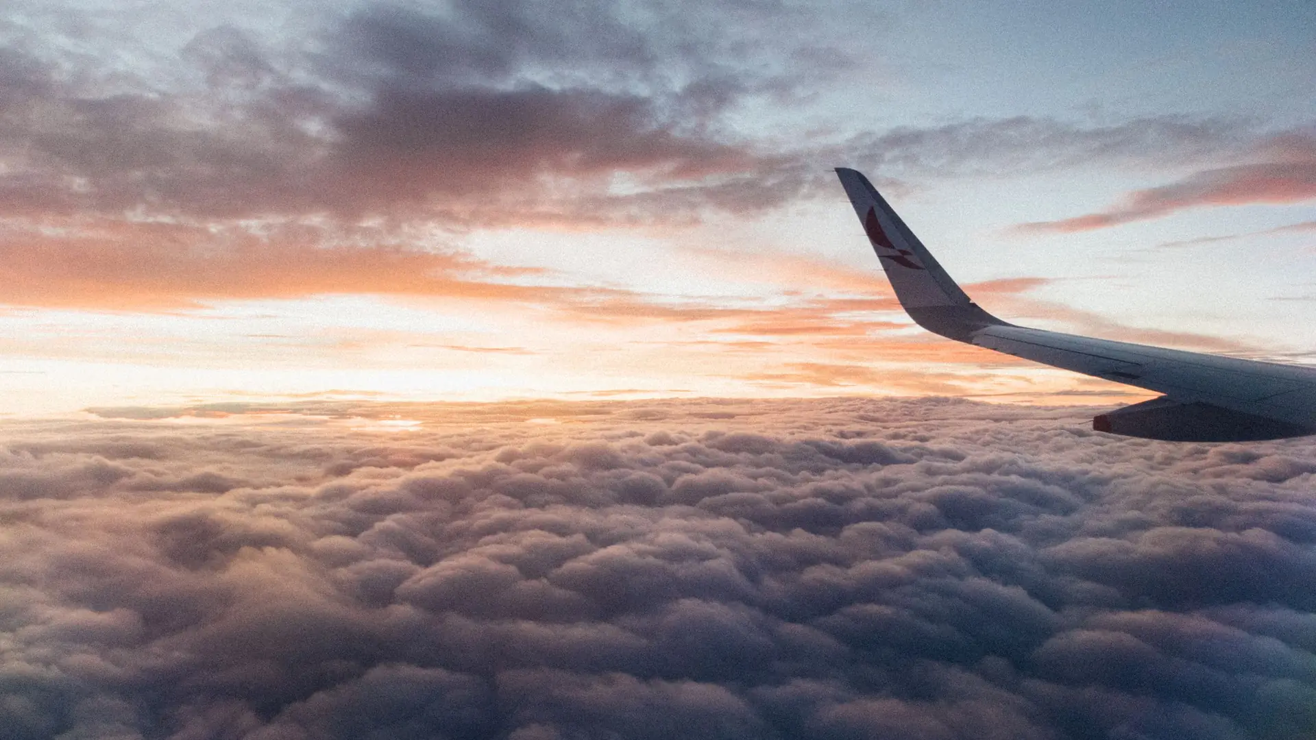 An aircraft wing above a sea of cloud at sunrise