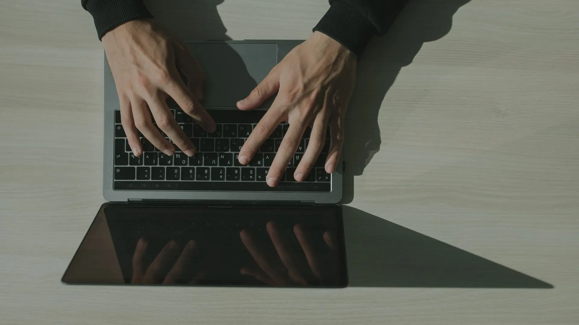 Hands typing on a laptop, seen from directly above