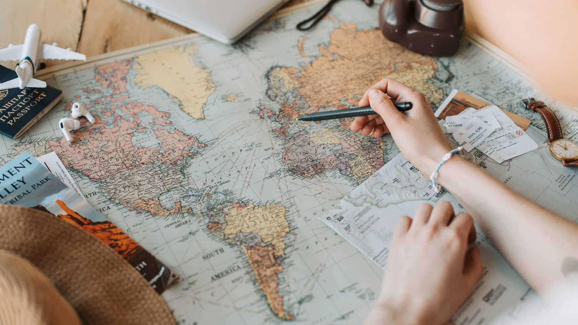 Hands tracing a route across a paper world map