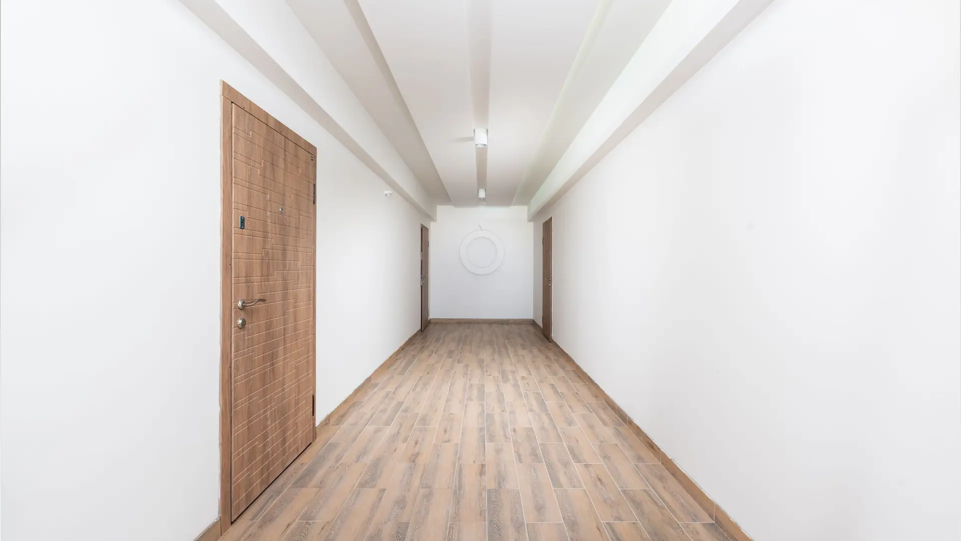 A bright empty corridor leading to a wooden door