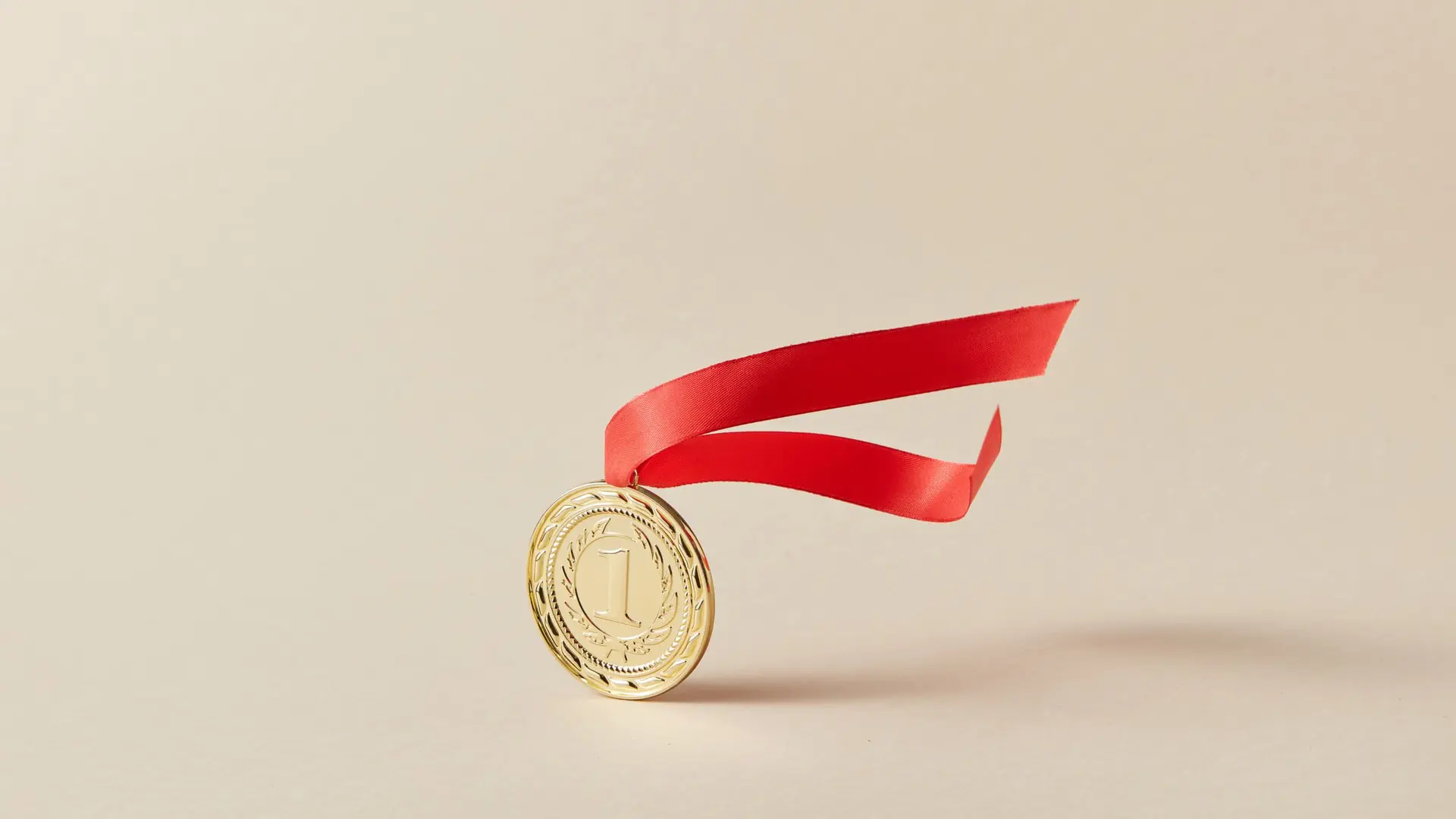 A gold medal with a red ribbon on a warm paper background