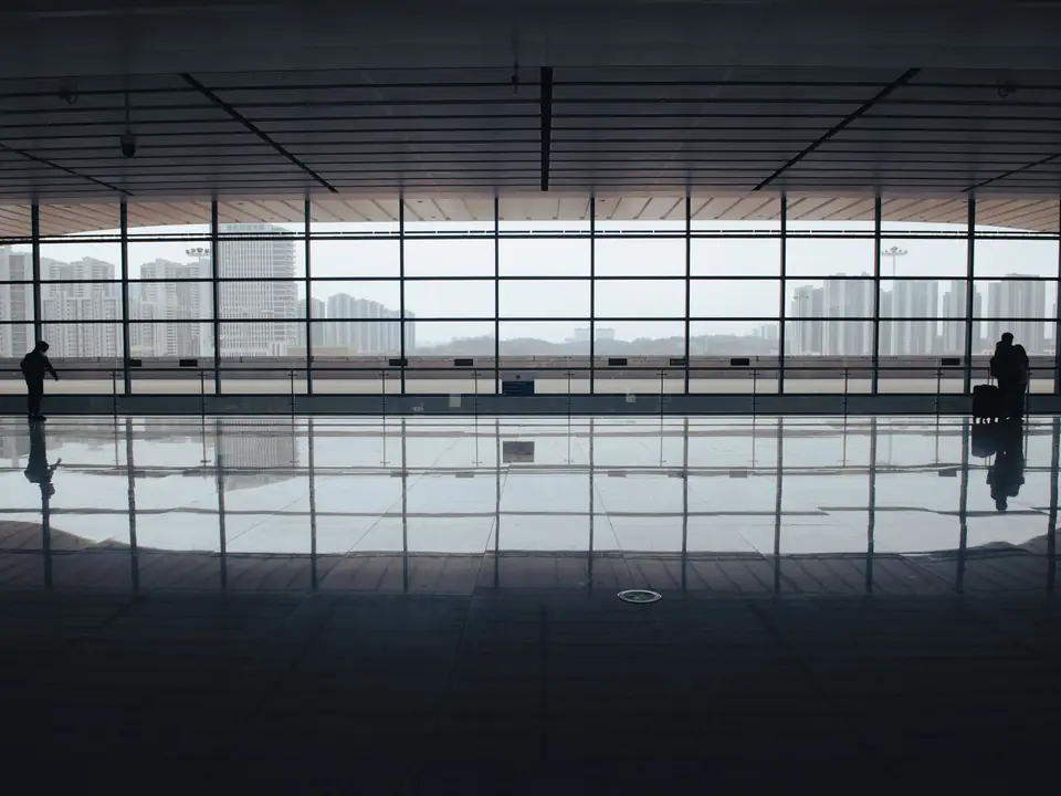 A lone traveller beside the tall windows of an airport terminal