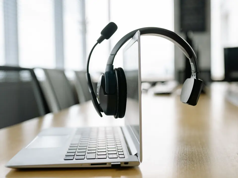 A headset resting on an open laptop in a bright office