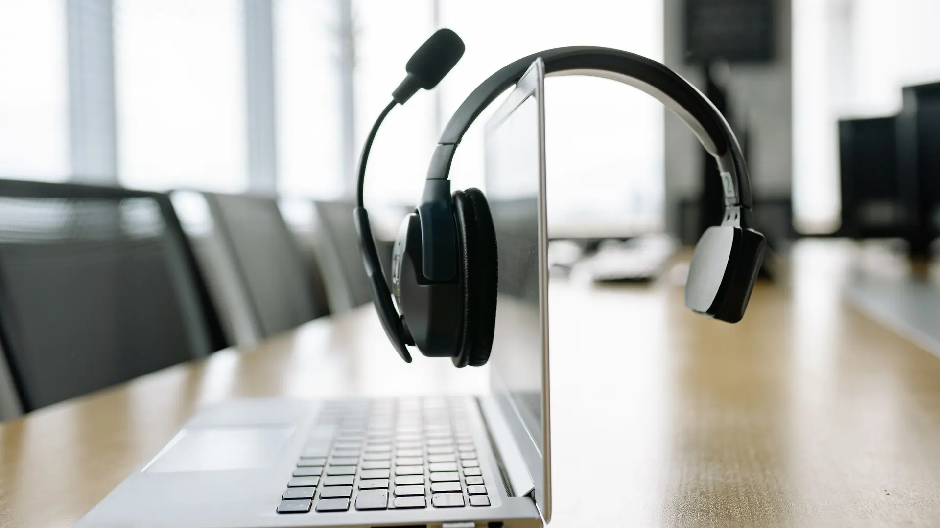 A headset resting on an open laptop in a bright office