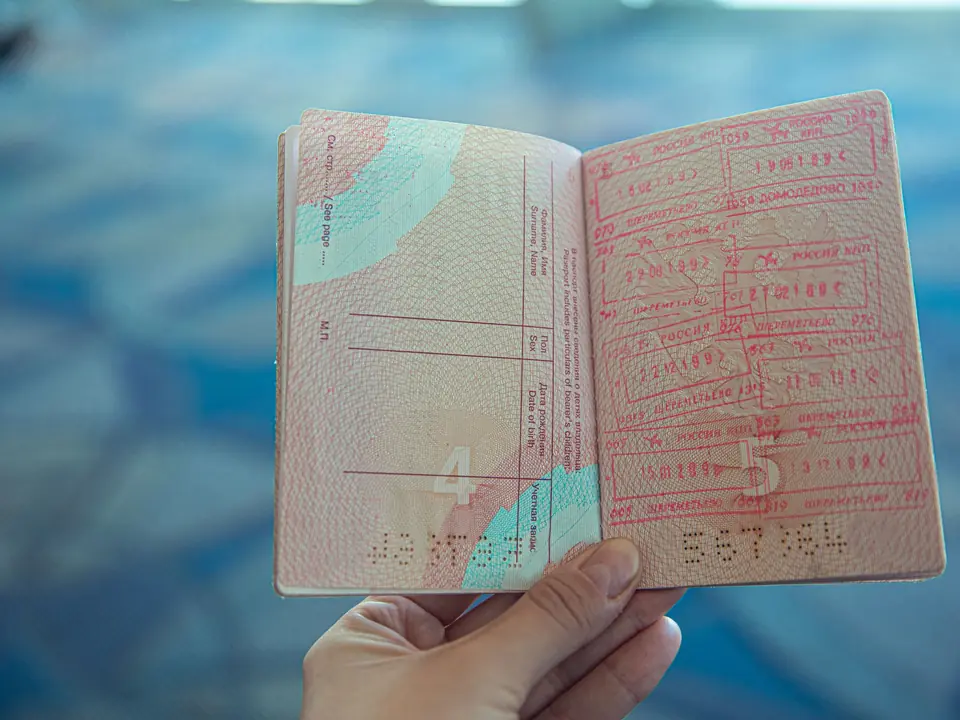 A hand holding a passport open at pages of entry stamps