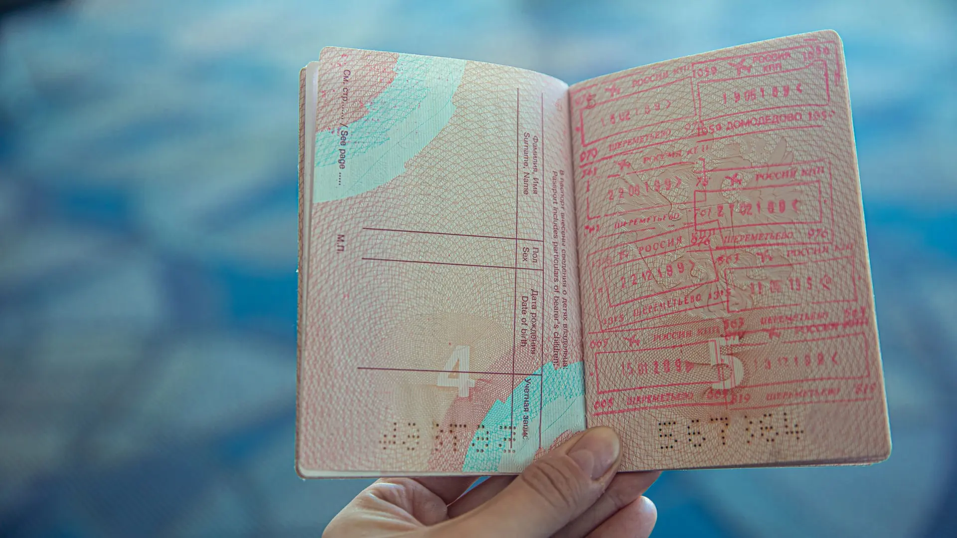 A hand holding a passport open at pages of entry stamps