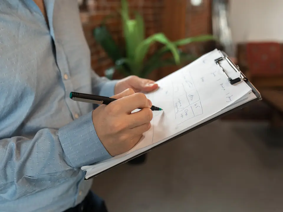 A hand ticking items on a clipboard checklist