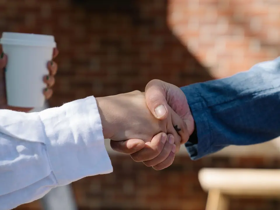 Two people shaking hands across a table, seen close up