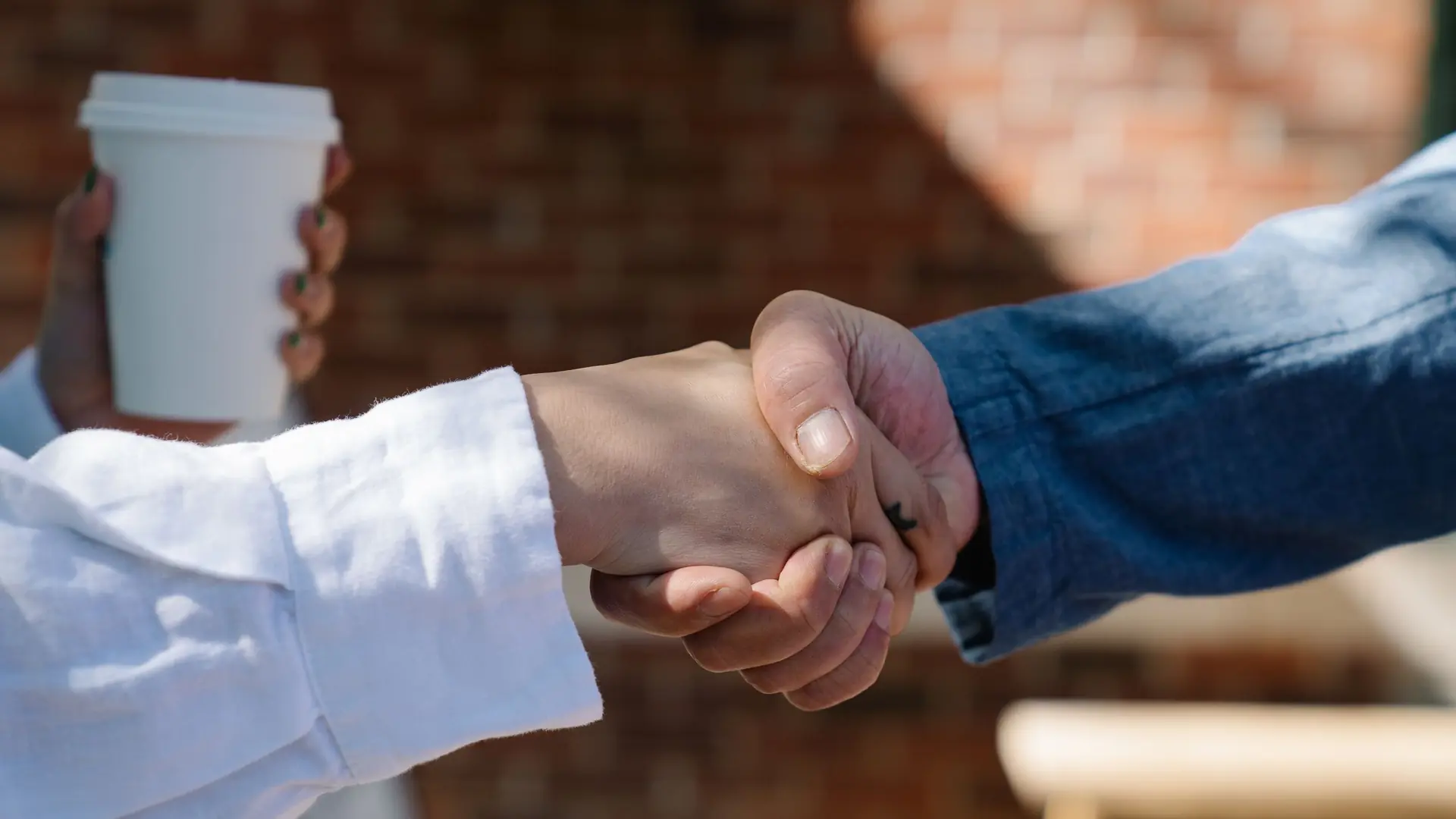 Two people shaking hands across a table, seen close up