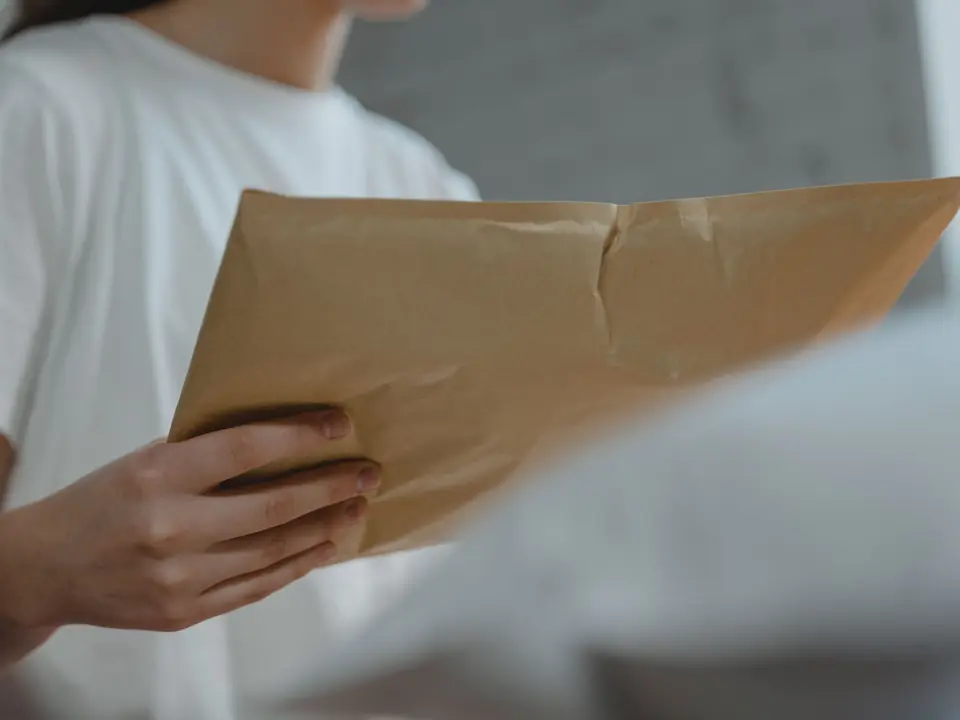 Hands holding a sealed kraft-paper courier envelope
