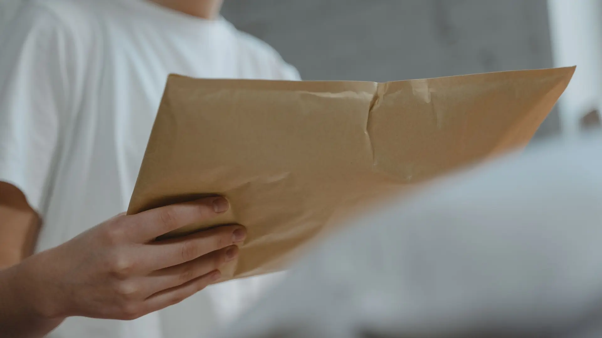 Hands holding a sealed kraft-paper courier envelope