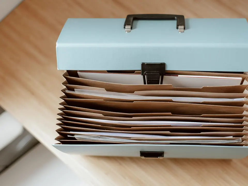 An open file box holding neatly ordered paper documents
