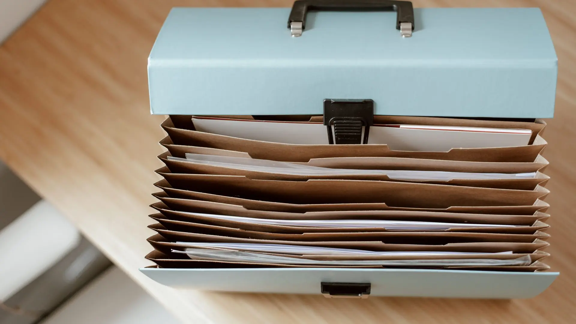 An open file box holding neatly ordered paper documents