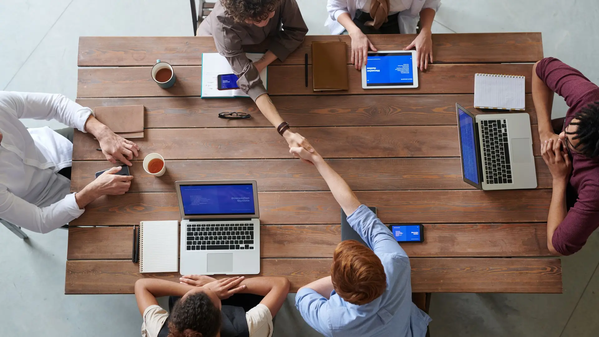 A team around a wooden table with laptops, seen from above